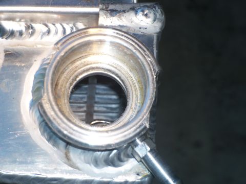 1979 Ford Ranchero - Extreme close-up of the filler neck on a polished aluminum radiator, showing stacked TIG weld beads around the neck and top tank seam with…