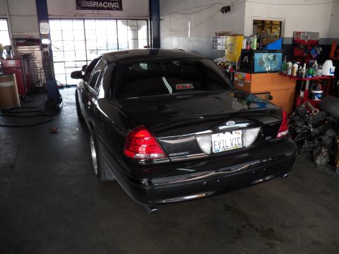 2003 Ford Crown Victoria - Rear quarter of a black Crown Victoria parked in a garage with Racing banner, plate reads EVIL VIC.