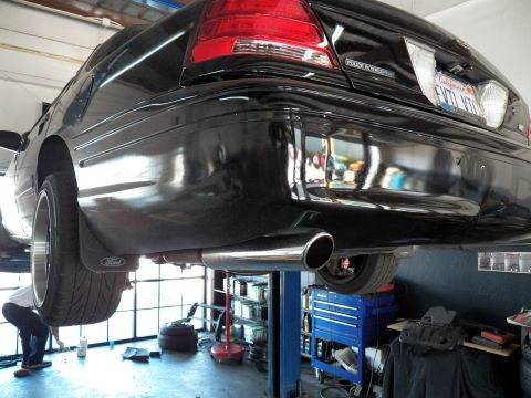 2003 Ford Crown Victoria - Low rear view of a lifted Crown Victoria showing chrome exhaust tip and Ford-branded mud flap.
