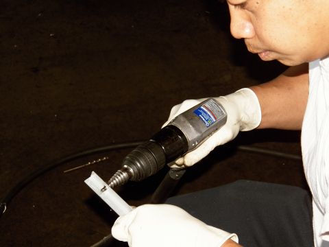 2003 Ford Crown Victoria - Close-up of a worker drilling a mounting bracket while wearing latex gloves in a garage.