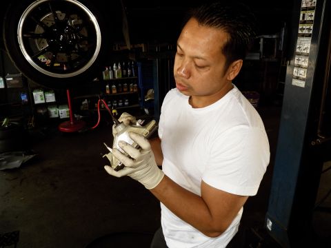 2003 Ford Crown Victoria - Worker holds a chrome automotive component near a tire display inside a service bay.