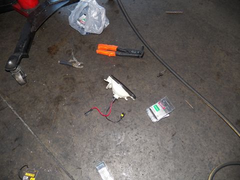 2003 Ford Crown Victoria - Disassembled lighting parts, wiring and an orange tool spread across a concrete shop floor.