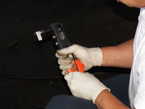 2003 Ford Crown Victoria - Close-up of latex-gloved hands operating an orange-handled clamping tool.