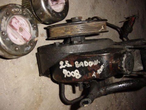 1992 Ford Bronco - A power steering pump and two hubcaps are shown close-up on a concrete surface.