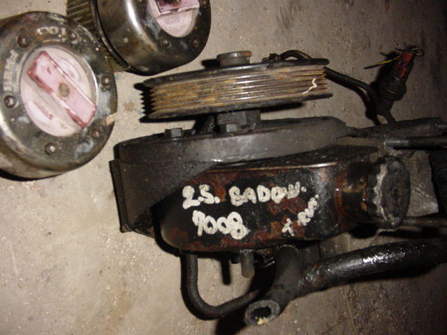 Power steering pump with handwritten "2.S. BADOW 9008" and two hubcaps
