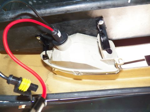 2003 Ford Crown Victoria - Headlight housing fitted with bulb and red lead positioned on a tan body panel.