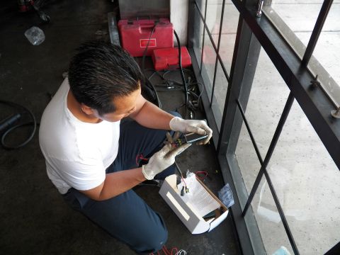 2003 Ford Crown Victoria - Worker assembles wiring over a small box on the floor near red tool cases.