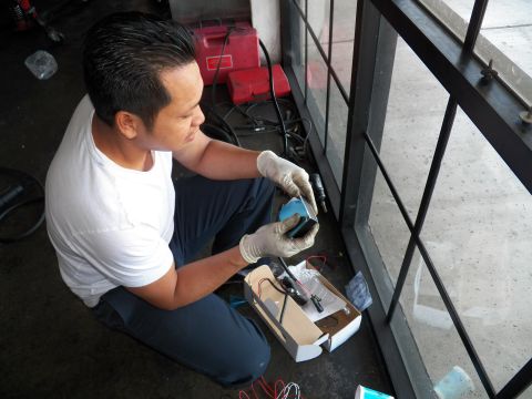 2003 Ford Crown Victoria - Worker handles a blue ballast unit and wiring over a small box in the service bay.