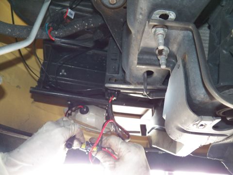 2003 Ford Crown Victoria - Underbody work showing hands joining a connector beneath a black tray and white housing