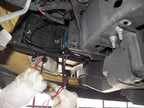 2003 Ford Crown Victoria - Technician attaches red and black wires to a bracket on the underside of a raised vehicle