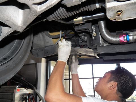 2003 Ford Crown Victoria - Technician works on the underside of a car near the steering rack boot and front suspension