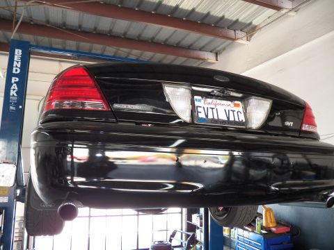 2003 Ford Crown Victoria - Tail detail of a black Crown Victoria showing Police Interceptor script and dual exhaust tip