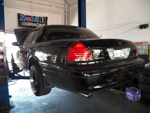 2003 Ford Crown Victoria - Lowered black Crown Victoria on black wheels, rear corner, under a Mobil 1 Racing sign