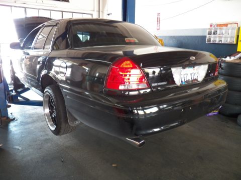 2003 Ford Crown Victoria - Black Crown Victoria photographed from the left rear in a tire shop, EVTL VTC plate