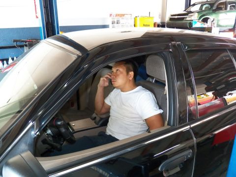 2003 Ford Crown Victoria - Person seated behind the wheel of a black sedan in a shop bay, talking on a phone