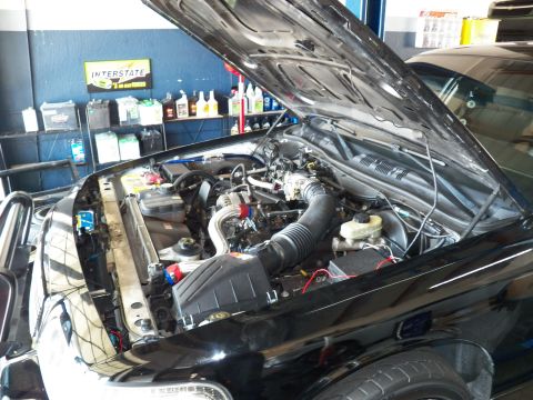 2003 Ford Crown Victoria - Engine compartment of a black Ford under the raised hood, Interstate Batteries display behind