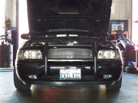 2003 Ford Crown Victoria - Close front view of a black Crown Victoria, push bar over billet grille, EVIL VIC plate