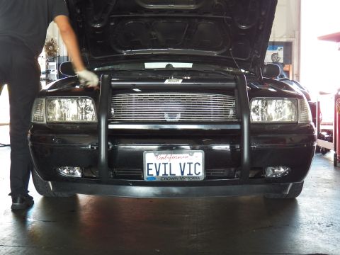 2003 Ford Crown Victoria - Billet grille and push bar of a black Crown Victoria, technician at left, EVIL VIC plate