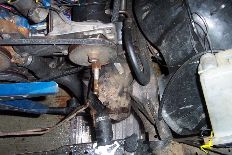 Engine compartment with belts, pulleys, hoses, and a power steering pump