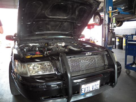2003 Ford Crown Victoria - Three-quarter front of a black Crown Victoria with push bar and billet grille, hood raised