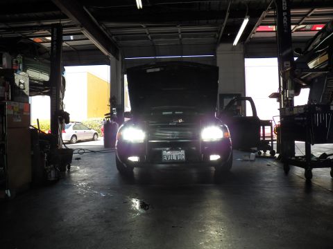 2003 Ford Crown Victoria - Black Crown Victoria with headlights illuminated and hood raised in a dim repair bay