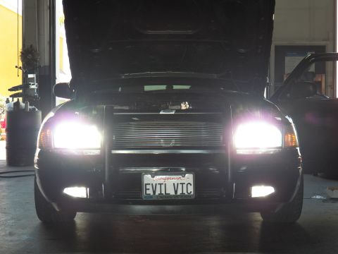 2003 Ford Crown Victoria - Garage shot, low front angle: blacked-out Crown Vic, brush guard, lit HIDs, California EVIL VIC plate