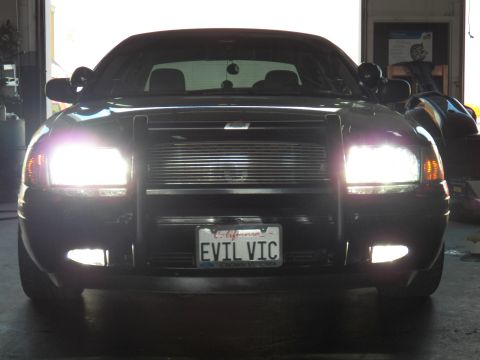 2003 Ford Crown Victoria - Front close-up in a service bay; California plate reads EVIL VIC, twin spotlights on A-pillars