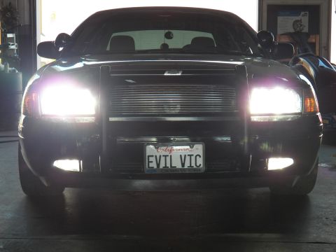 2003 Ford Crown Victoria - Shop-bay front; EVIL VIC California plate, CROWN VICTORIA frame, A-pillar spotlights visible