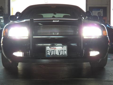 2003 Ford Crown Victoria - Low front angle in shop; brush guard over billet grille, EVIL VIC plate, fog lights on