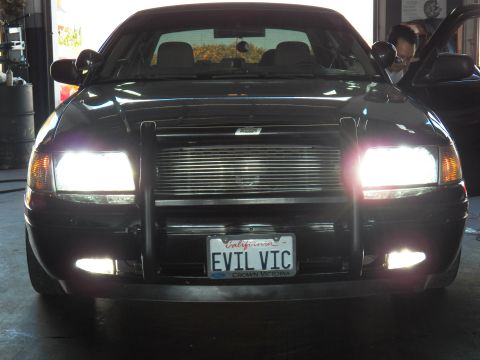 2003 Ford Crown Victoria - Front shot in service bay; EVIL VIC California plate, twin spotlights, mechanic at right