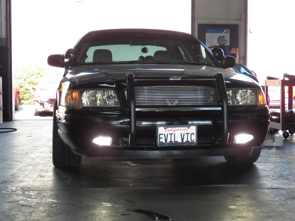 Black Ford Crown Victoria with brush guard and billet grille parked in open garage bay