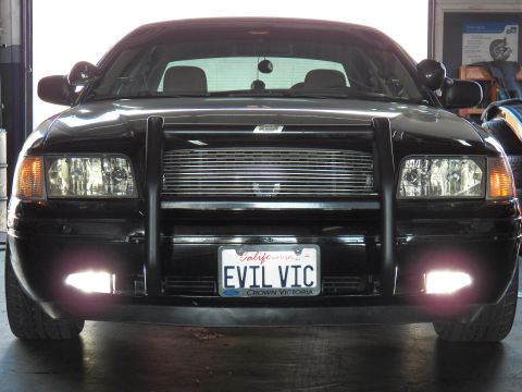 2003 Ford Crown Victoria - Black Ford Crown Victoria front close-up, grille guard and fog lights, California EVIL VIC plate, garage interior.