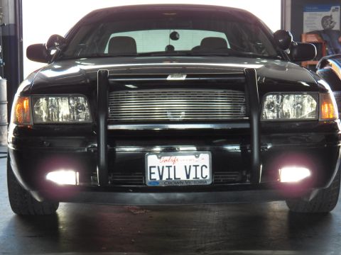 2003 Ford Crown Victoria - Front view, shop bay; CROWN VICTORIA plate frame under EVIL VIC tag, fog lights on
