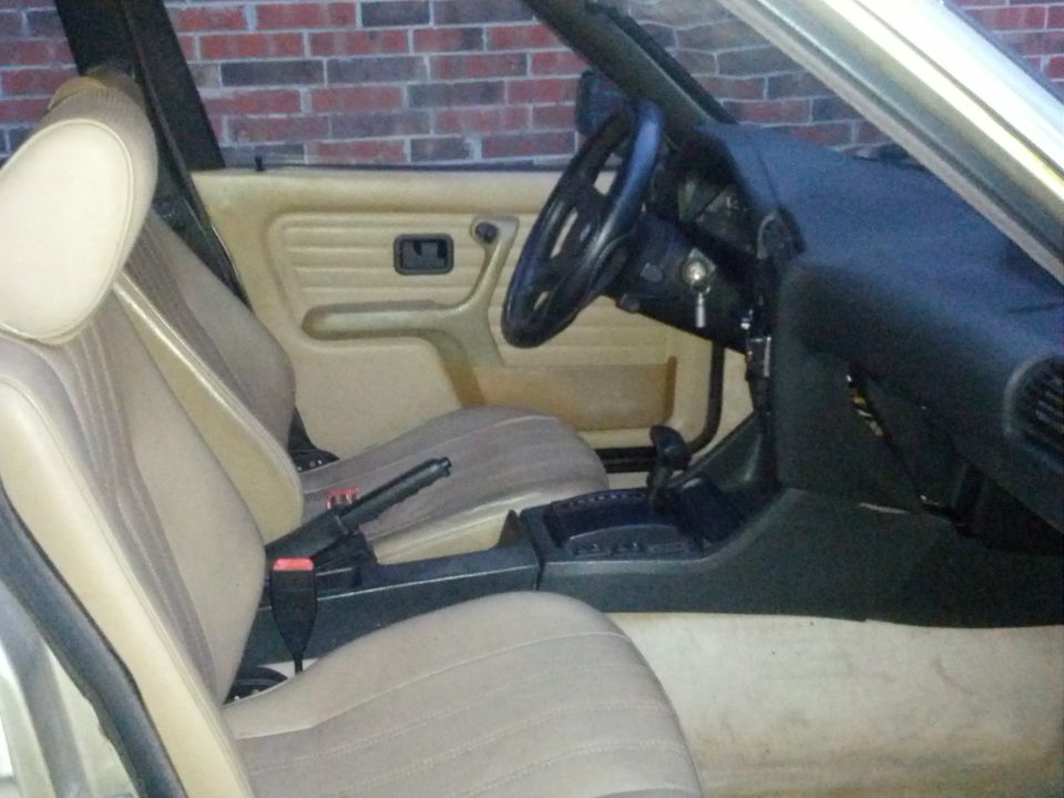 Interior view of a 1989 BMW 3 Series showing tan seats, dashboard, steering wheel, and center console