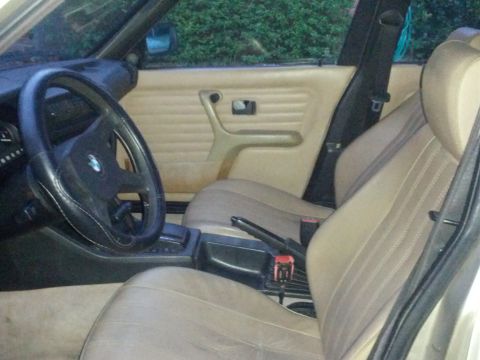 1989 BMW 3 Series - The interior of a 1989 BMW 3 Series features tan seats and door panels, with a black steering wheel.