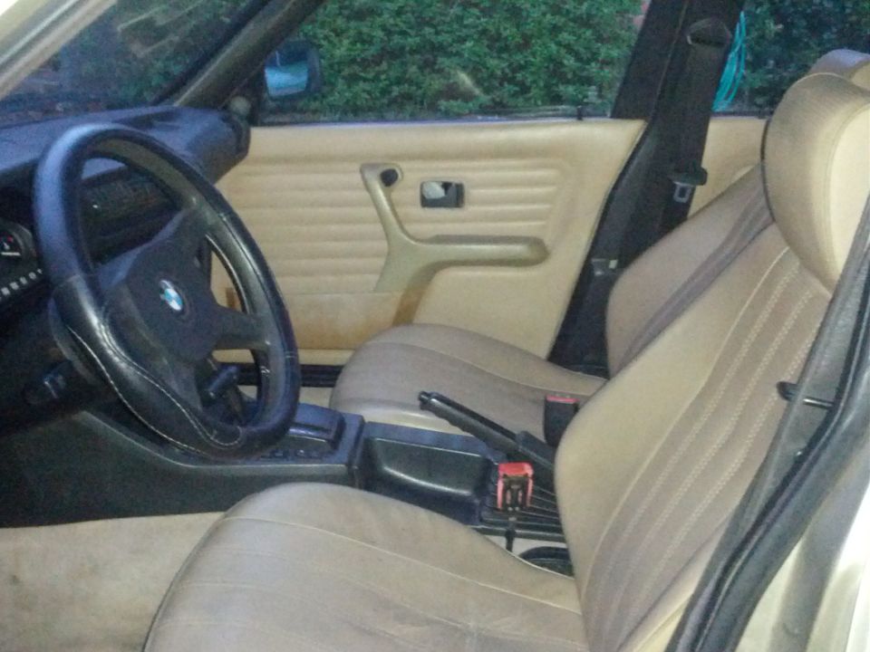 Interior shot of a 1989 BMW 3 Series showing the driver's seat, steering wheel, and door panel