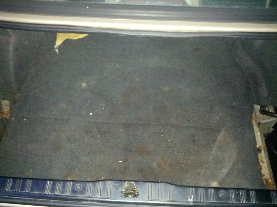 Interior of a car trunk with dark carpet and a metal latch