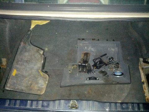 1989 BMW 3 Series - Disassembled car trunk interior shows various plastic and metal parts, suggesting a repair or modification in progress.
