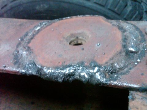 1986 Ford Bronco - This photo shows a close-up of a rusty metal component with visible welding marks and a central hole.