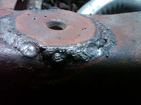1986 Ford Bronco - Close-up of a heavily welded metal component, showing signs of repair and rust.