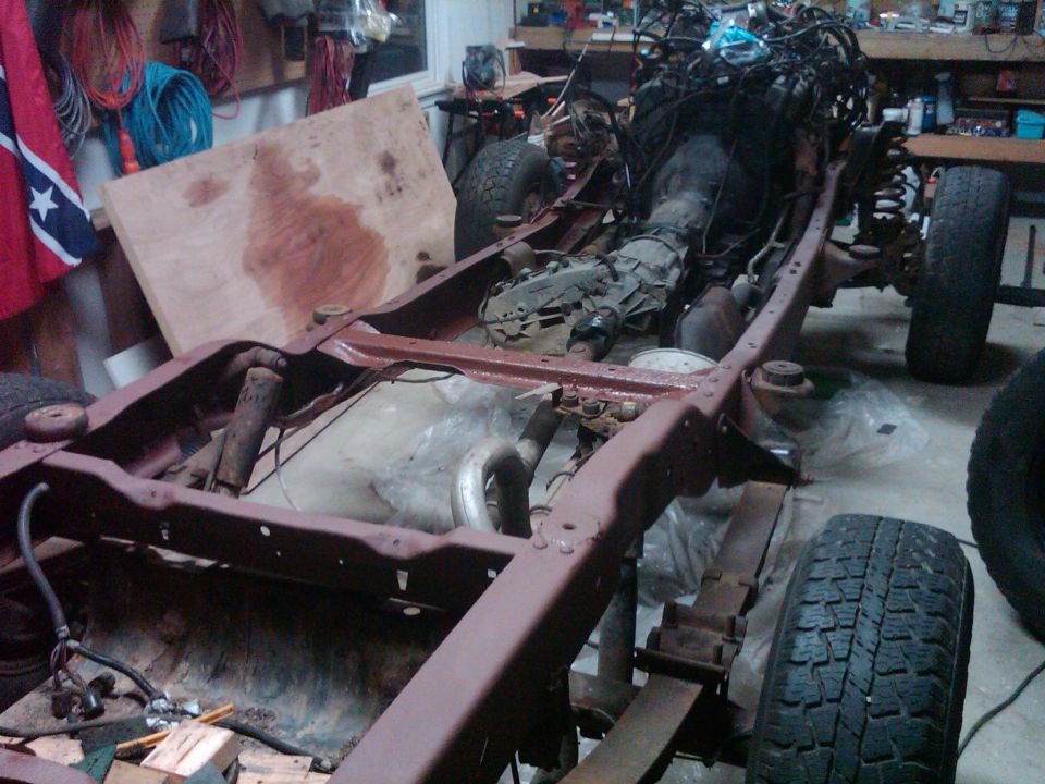 Vehicle frame with engine and transmission in a garage, partially disassembled