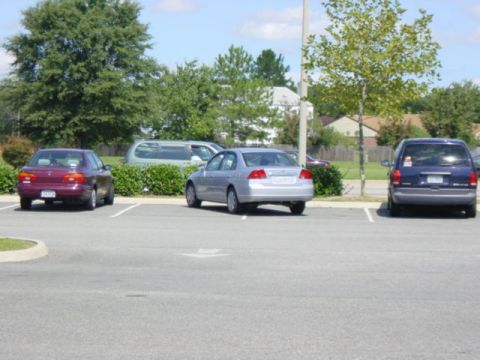 2003 Mazda 6 - A silver sedan is parked in a lot, viewed from the rear. Other vehicles are also present in the parking lot.