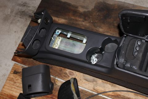 2003 Ford Crown Victoria - Car interior center console parts laid out on a wooden surface for repair or modification.