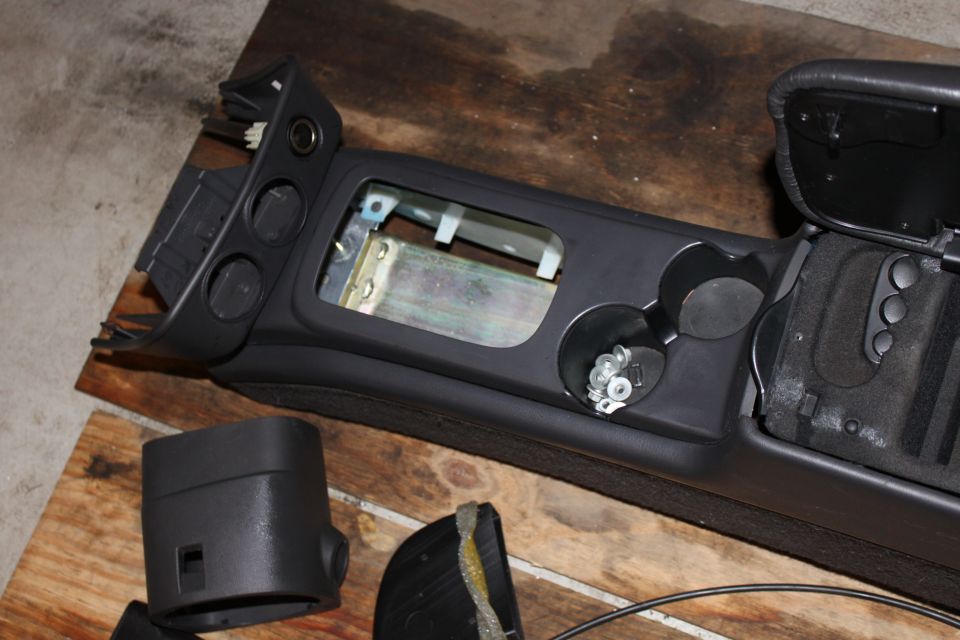 Disassembled car center console with cup holders and wiring visible