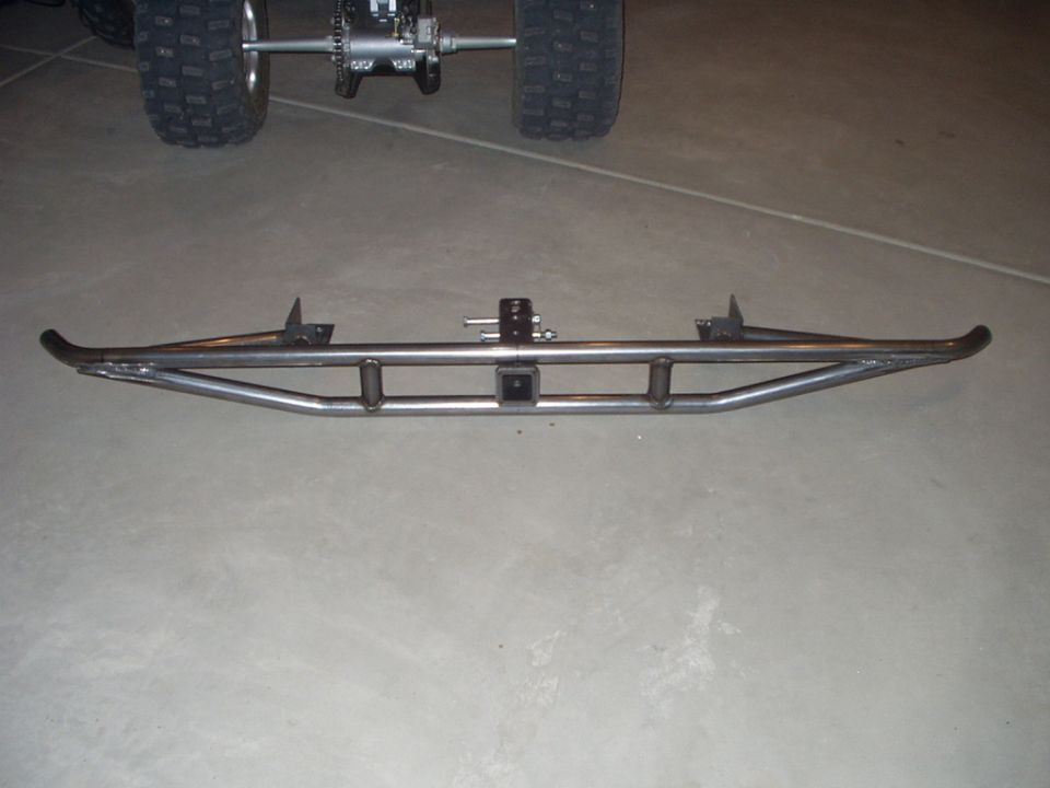 Bare steel tubular rear bumper with hitch receiver on garage floor