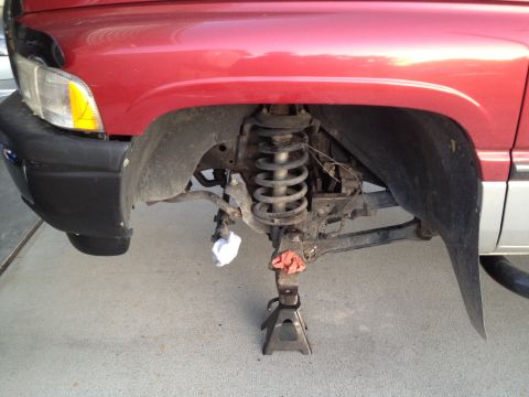 1997 Dodge 2500 - Front suspension of a red pickup truck is visible, supported by jack stands.