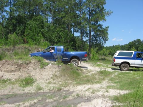 1994 Ford Bronco - A blue Ford F-150 is being towed out of a ditch by a Ford Bronco.