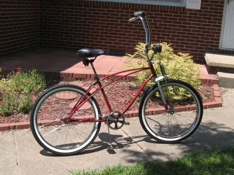 1994 Ford Bronco - A red cruiser bicycle with whitewall tires sits on a sidewalk in front of a brick house.