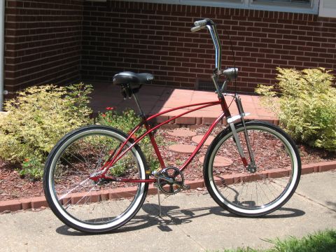 1994 Ford Bronco - A red cruiser bicycle with whitewall tires and chrome handlebars is parked on a sidewalk in front of a brick building.