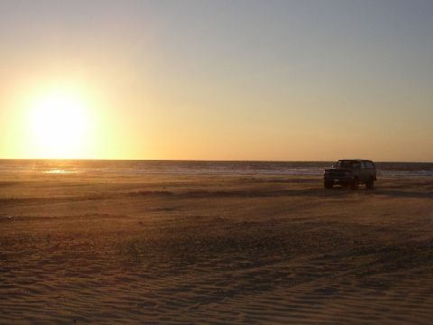 1989 Ford Bronco - SUV on beach during sunset.